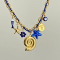 Gros plan détaillé du pendentif coquille dorée et étoile de mer bleue sur le collier - Thème Océan Étoile de Mer / Étoile de Mer Bleue