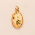 Detalle de un colgante ovalado vintage con marco dorado y diseño floral pintado a mano - Flor Blanca Ovalada (No. 2)