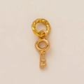 Gros plan d'un pendentif clé dorée au fini poli avec une bélière torsadée de style vintage - Badge porte-clés