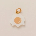 Gros plan détaillé d'un pendentif œuf au plat avec anneau doré sur fond beige - Pendentif Œuf au plat