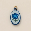 Macro detail of oval ceramic floral pendant with blue flower and gold ring - Blue Flower Pendant