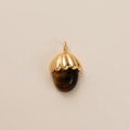 Detalle de un colgante de bellota en metal dorado texturizado y piedra de ojo de tigre - Colgante de Avellana