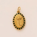 Detailed macro of a gold oval pendant with palm tree relief and green zircon stones - Green Rhinestone Palm Tree Pendant