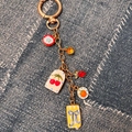 Détail de pendentifs de fruits colorés et de nœuds sur un porte-clés doré pour sacs - Pendentif Nœud Bleu