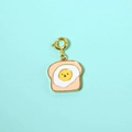 Macro detail of toast and smiling fried egg enamel pendant with golden lobster clasp - Pink Egg Toast Pendant
