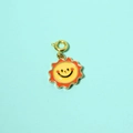 Detail of colorful sun charm with yellow smiling face and orange enamel coating - Sun Pendant