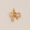 Gros plan d'un pendentif nœud doré avec pampille sertie d'un diamant étincelant - Petit Pendentif Nœud