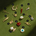 Collection of 13 gold-plated charms with colorful gemstones on a green background - No.1 Key Pendant
