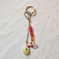 Vue macro d'un porte-clés doré 18 carats avec pendentif cerise et perles colorées - Cerise Cœur Violet Étiquette Fruit