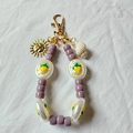Détail du porte-clés plaqué or 18K avec perles mauves, pendentif soleil et coquillage - Soleil Conque Naturelle Violet à Perles