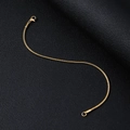 Detail view of a gold snake chain bracelet with a lobster clasp on black leather - 1.5mm x 20cm / Gold