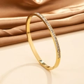 Detail showing the 18K gold plated steel bangle with sparkling CZ stones on silk fabric - Gold