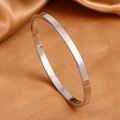 Detail view of 4mm silver stainless steel oval bangle with side clasp on silk background - Steel