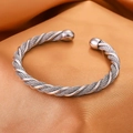 Primer plano de pulsera rígida trenzada plateada con puntas de bola sobre seda fina - Abierto Ajustable / Plateado