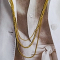 Detailed macro view of layered gold snake and rope chains on a stylish magazine - Triple Layer Style