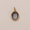 Macro detail of 18K gold-plated oval pendant with smoke gray faceted gemstone inlay - March Birthstone Pendant