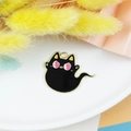 Detail van een schattige zwarte kat emaille hanger op een bord met gedroogde bloemen - Geestkat