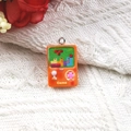 Detail of a retro orange resin game console charm with a metal ring on knit fabric - Bright Orange
