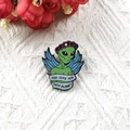 Green alien enamel pin with pink floral crown and Too Cute For This Planet ribbon - Angel Alien Style