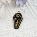 Détail d'un pendentif cercueil en émail noir avec croix dorée sur tricot blanc - Cercueil Noir avec Croix(15)