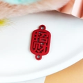 Vue macro d'un connecteur chinois Zhaocai rouge ajouré pour la création de bijoux - Appeler La Richesse / Rouge