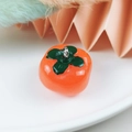 Vibrant orange resin persimmon pendant with green leaf and silver metal ring loop - Tomato