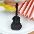 Detail van gitaarvormige acryl hanger met witte glitters op een zwart oppervlak - Gitaar
