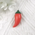 Macro detail of realistic red resin chili pendant with green stem and silver metal hook - Red