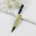 Close-up of a miniature Halloween chef knife charm with a golden mirror finish - Gold