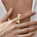Exaggerated gold bow-knot ring with irregular vintage texture worn on a hand - Knotted Bowknot Style (KR0174)