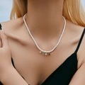Detailopname van een parelketting met vier kleurrijke hartvormige hangers bij een model - Vierkleuren Hart Edelsteen Hanger Parelketting (KN0434)