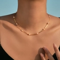 Elegante 18K vergulde parel choker ketting met Saturnus-ringen op een model - Saturnusring Parel Goud (KN0573-1)