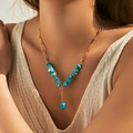 Detail van bohemien gouden paperclipketting met onregelmatige turquoise hanger op model - Paperclip Ketting Blauwgroene Steenfragmenten (KN0531)