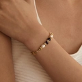 Elegante bracciale di perle con pietre viola e ciondoli dorati indossato al polso - Stile Perlato con Perla Barocca e Grani Viola (KB0750)