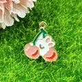 Detailed shot of an enamel bunny and pink cherry charm pendant with gold metal ring - Cherry Rabbit