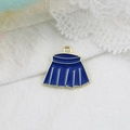 Detail shot of a blue pleated skirt enamel alloy charm on white textured fabric background - Blue Skirt