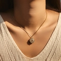 Golden sunburst compass pendant necklace with red gemstone on model with beige knitwear - Red Stone Compass Style (SN0021-2)