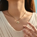 Gold sunflower necklace with black stone pendant worn on a beige knit sweater - Black Stone Sun Pattern Style (SN0022-1)