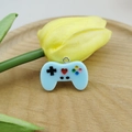 Close-up of a blue resin game controller charm with a metal ring on a wooden tray - Light Blue