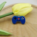 Macro shot of blue resin game controller charm with colorful buttons and metal ring - Dark Blue
