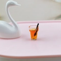 Vue macro d'un charm miniature en résine jus d'orange avec paille et tranches d'orange - Orange
