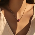 Collana dorata con ciondolo a forma di occhio rosa indossata sotto la luce del sole - Malocchio Rosa Scuro (SN0020-3) / Acciaio inossidabile
