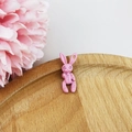 Close-up of pink matte rabbit pendant with stitch texture on wooden tray with pink flower - Pink Rabbit