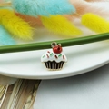 Macro shot of an alloy enamel cupcake pendant with cream and cherry detail for DIY jewelry - Strawberry Cake Style