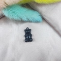 Detailed close-up of a black resin cartoon bear charm on champagne silk background - Black