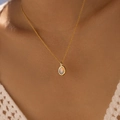 Detailed view of an oval moonstone pendant on a gold chain worn with a white crochet top - Milky White Translucent Gemstone Style (KN0611-5)