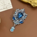 Nahaufnahme der Vintage-Brosche in Silber mit blauen Kristallen auf dunklem Leder - Blau