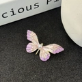 Makro-Detail der Emaille-Schmetterlingsbrosche mit lila Verlauf und Perlen auf schwarzem Grund - Rosa-Lila Emaille Schmetterling