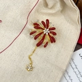 Detail of red zircon firework brooch with golden tassels and star pendant on linen - Red Tassel Firework Gold