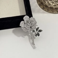 Dettaglio della spilla a rosa in argento con cristalli bianchi e neri sul vassoio - Spilla a Rosa/Camelia
